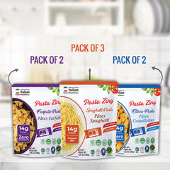 An infographic set against a blurred kitchen background showing purchasing options for Pasta Zing. The center Spaghetti pouch is labeled as part of a "PACK OF 3" (containing one of each variety). Arrows point to the side: the Farfalle pouch (left) and Elbow pouch (right) are labeled as available in "PACK OF 2" sets of their respective flavors. Each pouch highlights the 14g Protein content and the quick 1-minute cook time.